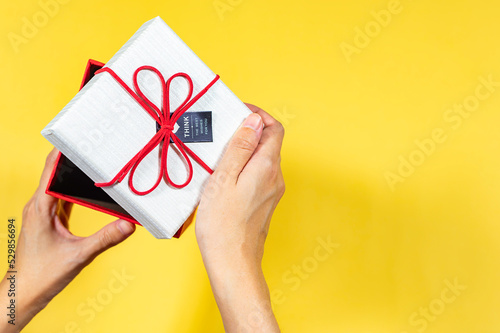 Fototapeta Naklejka Na Ścianę i Meble -  Hand open a present gift box on yellow background, Top view, Copy space, Holiday and present concept