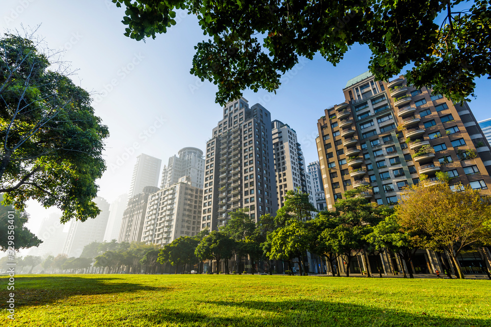Obraz premium Low angle view of park green space and modern buildings on both sides in downtown Taichung, Taiwan. here is near the National Taichung Theater.