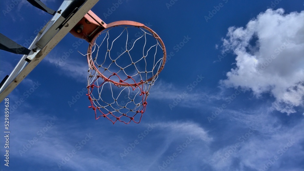 Under a basketball hoop with deep blue sky cloud in background Under a basketball hoop with deep blue sky cloud in background