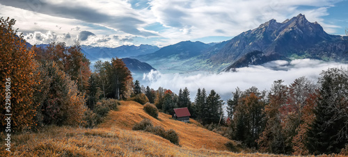 Picturesque autumn landscape. Panoramic view of stunning mountain scenery in the Alps with fresh green meadows with fog in mountains on a sunny morning in springtime, Switzerland