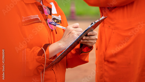 A safety supervisor or manager is writing down on paper for taking note during safety audit at the operation work site. Industrial safety working action scene, close-up and selective focus.