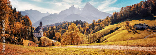 Stunning Autumn landscape. Scenic view on Maria Gern church with mountains on background. Vivid atmospheric nature scenery. Natural background. Iconic location for landscape photographers..Formats