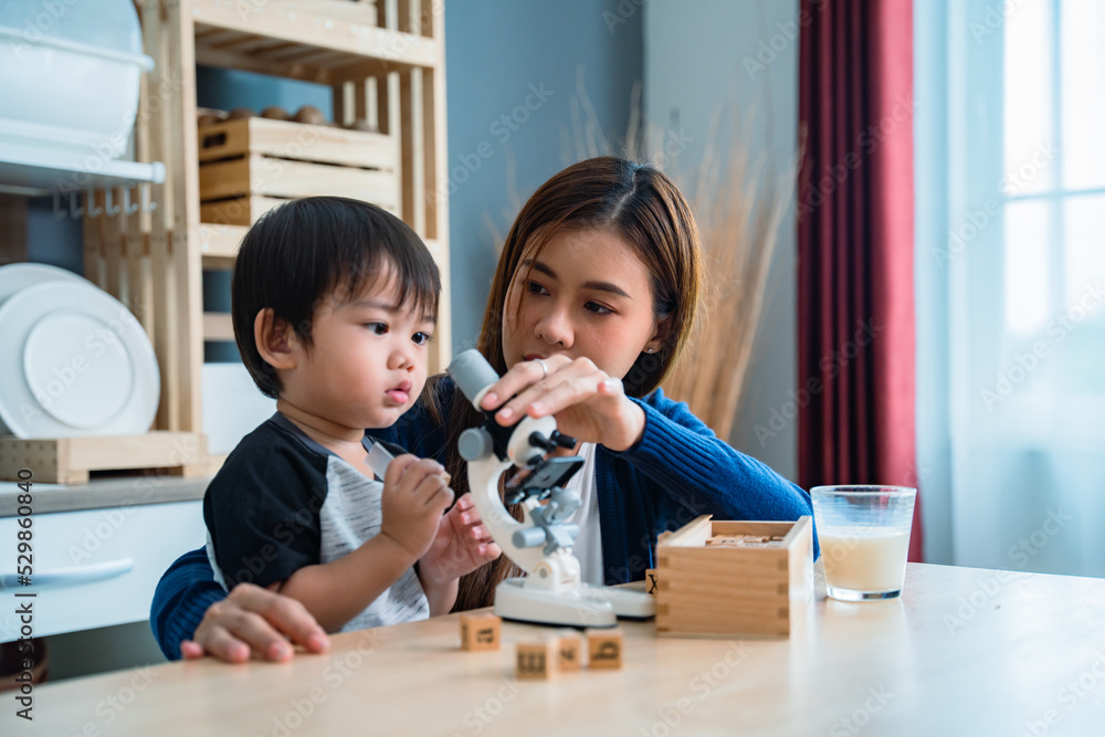 Asian baby boy playing microscope toys with his mother sitting beside. Asian baby boy playing microscope toys with his mother sitting beside.