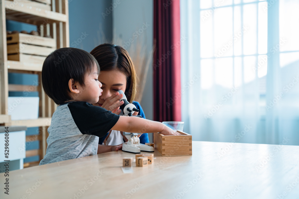Asian baby boy playing microscope toys with his mother sitting beside. Asian baby boy playing microscope toys with his mother sitting beside.