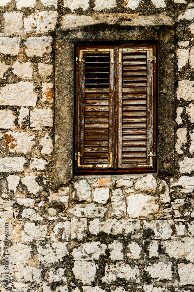 Stone wall and window with closed wooden shutters