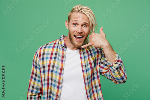 Young caucasian blond man with dreadlocks 20s he wear casual shirt doing phone gesture like says call me back isolated on pastel plain light green background studio portrait. People lifestyle concept.