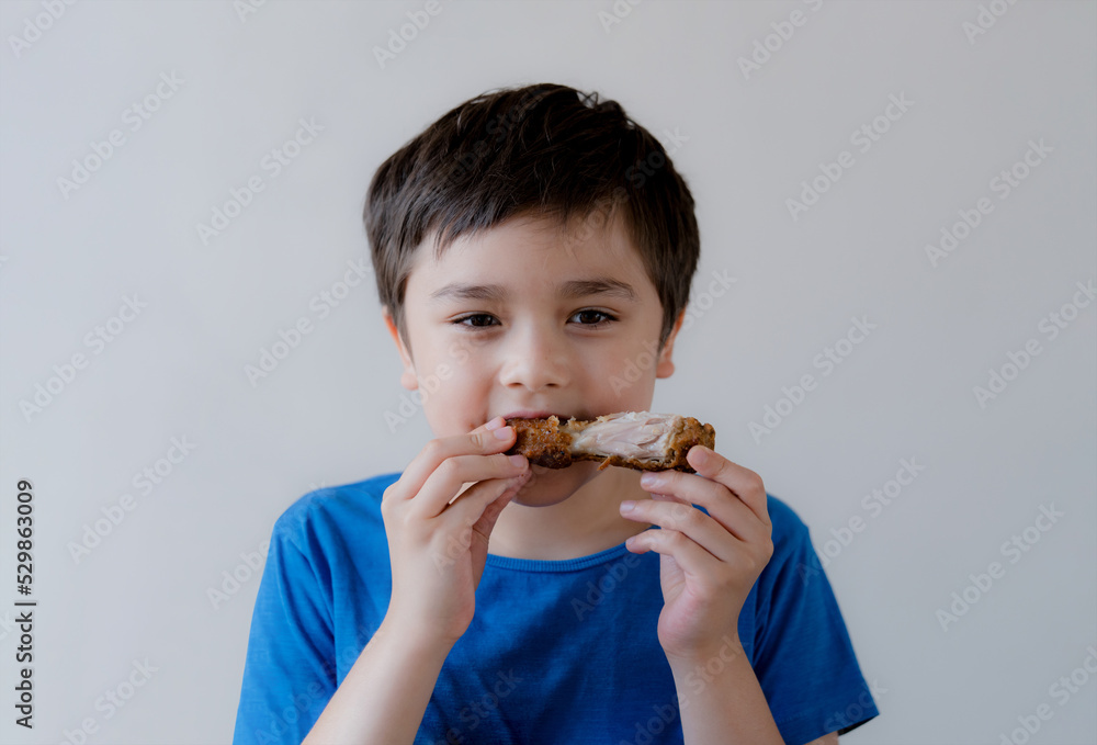 Portrait Kid with yummy face enjoy eating roasted chicken drumstick in the garden, Happy of cute boy eating grilled chicken, Healthy food for children concept Portrait Kid with yummy face enjoy eating roasted chicken drumstick in the garden, Happy of cute boy eating grilled chicken, Healthy food for children concept