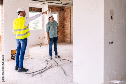 Young construction engineer discussing with architect worker at indoor building site