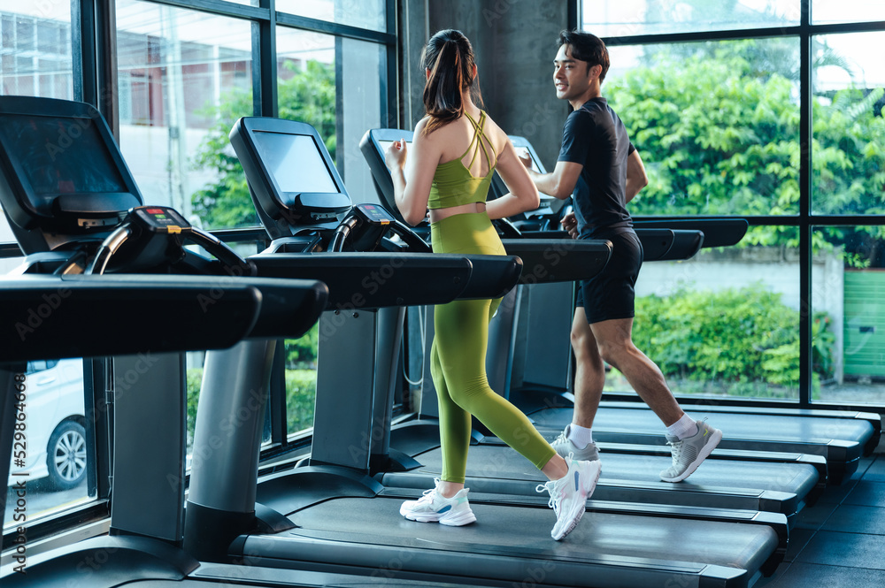 Together Asian man and woman healthy in sportswear cardio exercise jogging  on a treadmill in fitness gym. Sport people workout indoor for good health.  Healthy lifestyle concept. Stock-Foto | Adobe Stock