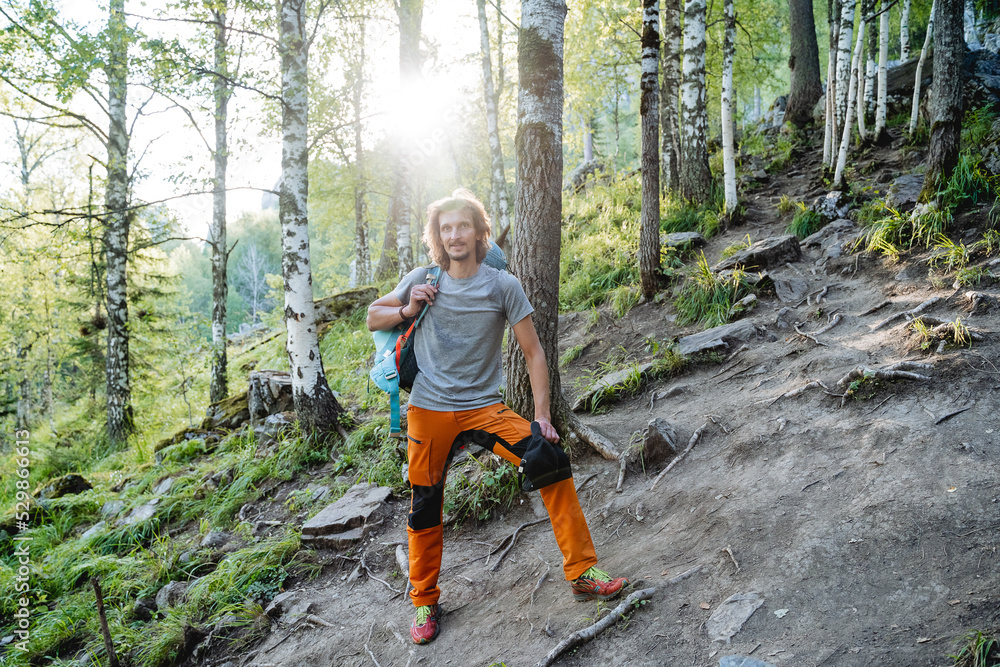 A halt on a mountain road, a guy resting in the forest, summer vacations in the mountains, a hard climb to a mountain peak, orange pants, thick hair, one in the taiga A halt on a mountain road, a guy resting in the forest, summer vacations in the mountains, a hard climb to a mountain peak, orange pants, thick hair, one in the taiga