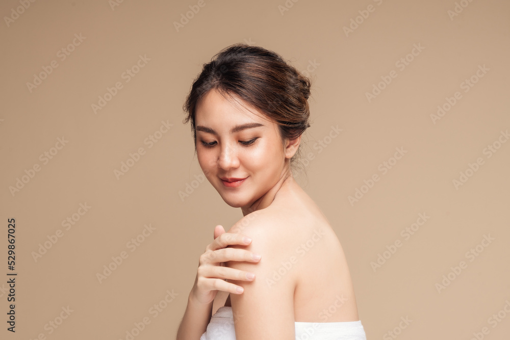 Beautiful asian woman showing perfect skin on her shoulder in isolated beige background. Young female beauty skin glowing hydrated and natural makeup. Beautiful girl skin care concept. Beautiful asian woman showing perfect skin on her shoulder in isolated beige background. Young female beauty skin glowing hydrated and natural makeup. Beautiful girl skin care concept.