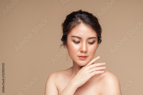 Beautiful Asian woman healthy facial skin face glowing hydrated and natural makeup on beige background. Young female beauty with perfect skin makeup. Beautiful female skin care foundation concept.