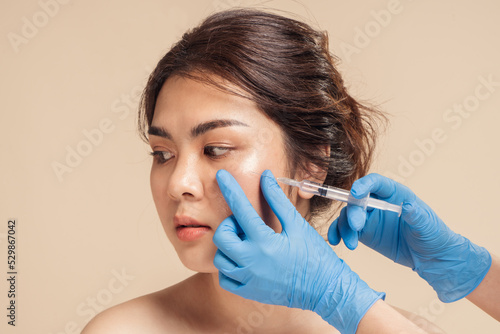 Принти на полотні Closeup face young asian woman is getting filler under her eye for anti age wrinkle by a beautician with a syringe in hands