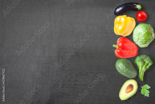 Vegetables on a dark background - sweet pepper, avocado, broccoli, eggplant and tomato