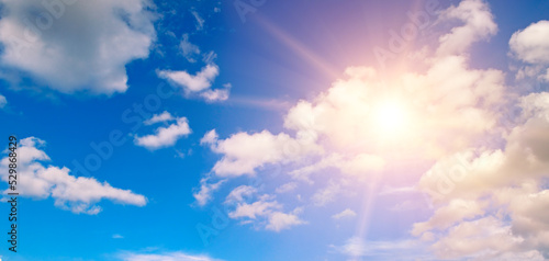 Beautiful  blue sky with fluffy clouds and bright sun as a background