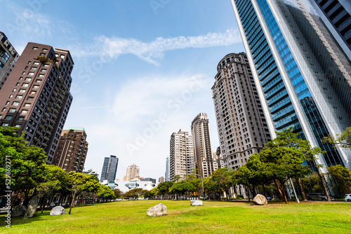 The large park green space in front of the National Taichung Theater in Taiwan and the landscape of modern buildings on both sides.