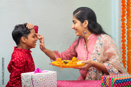 Sister applying tika on her brother's forehead on the occasion of Raksha Bandhan photo