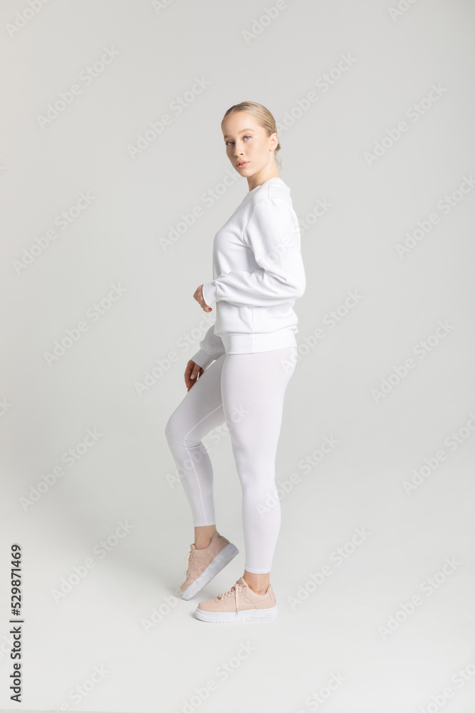 Attractive blonde woman in white sweatshirt and leggings on white background. Mock-up. Attractive blonde woman in white sweatshirt and leggings on white background. Mock-up.