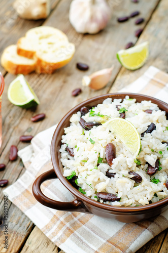 Coconut lime rice with red beans and cilantro in a bowl on a wood background