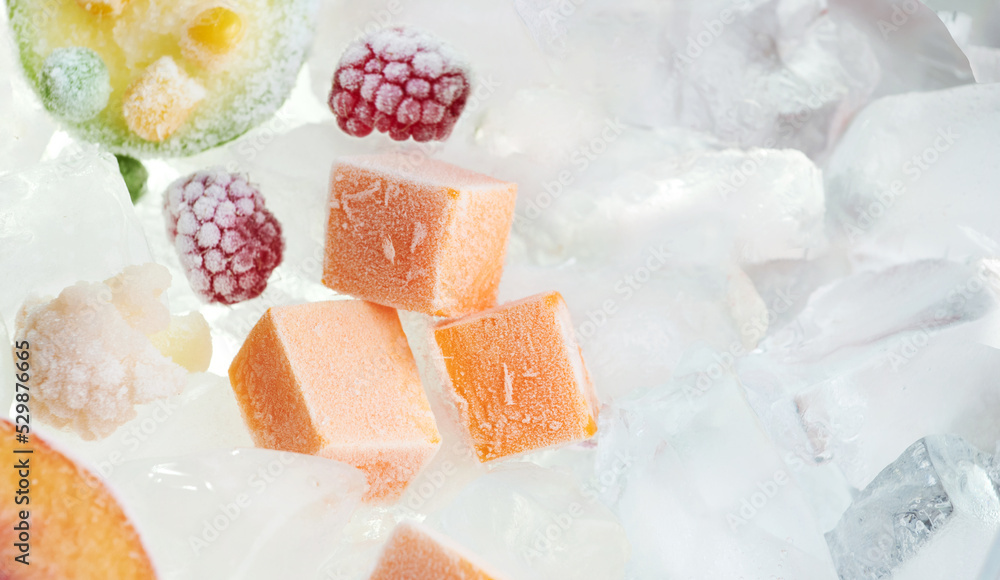 Closeup frozen chopped bricks vegetables (pumpkin) on ice. Stocks of food. View above.