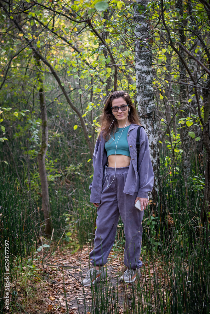 Portrait of romantic woman at fairy forest. A beautiful young girl with glasses is walking through the forest. Girl purple suit. Corduroy fabric Portrait of romantic woman at fairy forest. A beautiful young girl with glasses is walking through the forest. Girl purple suit. Corduroy fabric