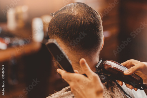 Barbershop vintage color. Man in barber chair, hairdresser master working with clipper and comb © Parilov