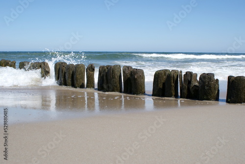 Beautiful coast of the Baltic Sea in Poland. Endless sandy beach, sea water waves. Wooden palisade by the sea. photo