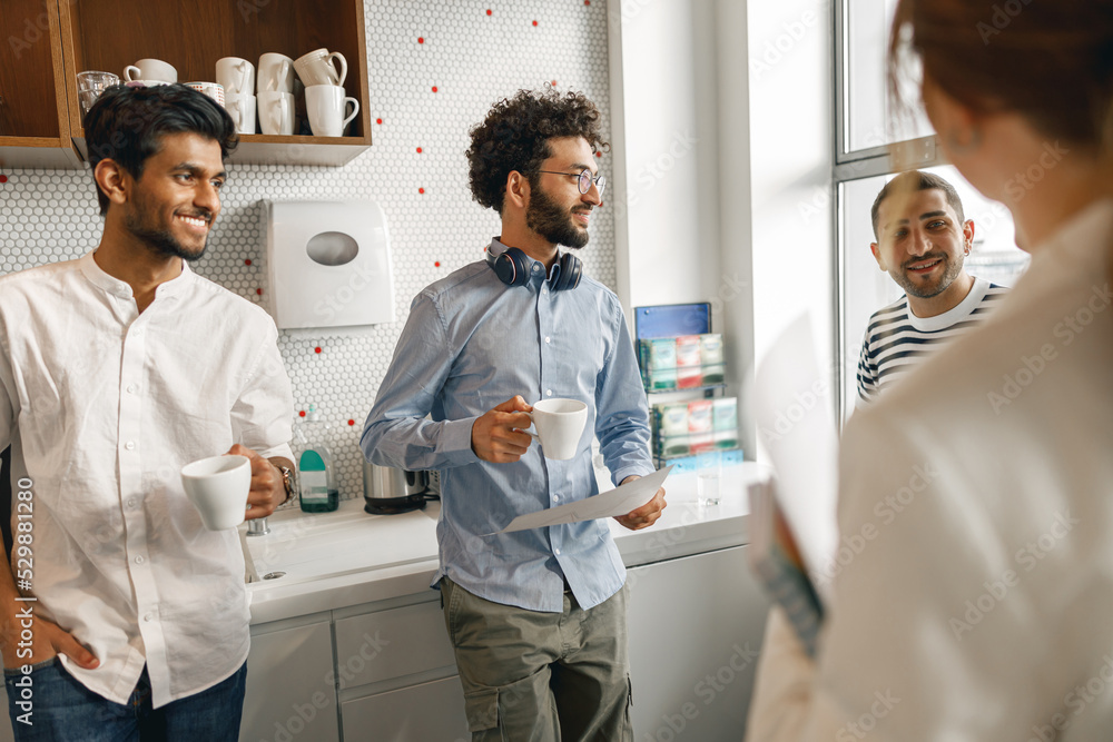Fototapeta premium Group of diverse coworkers drink coffee during break and talking about work project