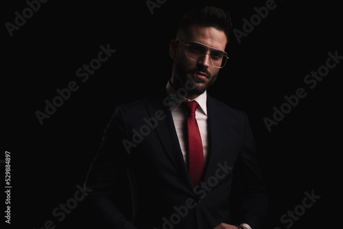 unshaved young guy in elegant black suit with red tie and eyeglasses
