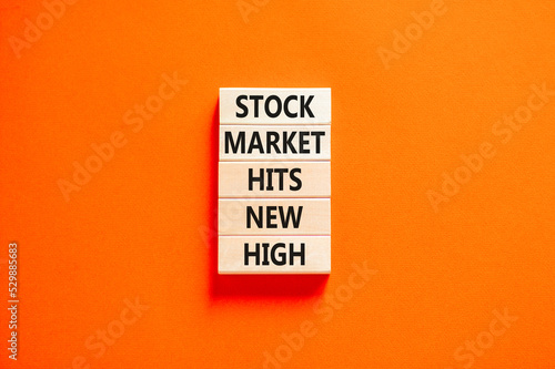 Stock market hits new high symbol. Concept words Stock market hits new high on wooden blocks on a beautiful orange table orange background. Business and stock market hits new high concept. Copy space.