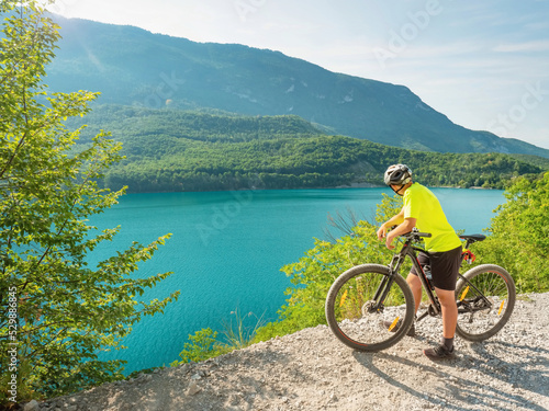 Young biker looking over Molveno lake from gravel trail round around