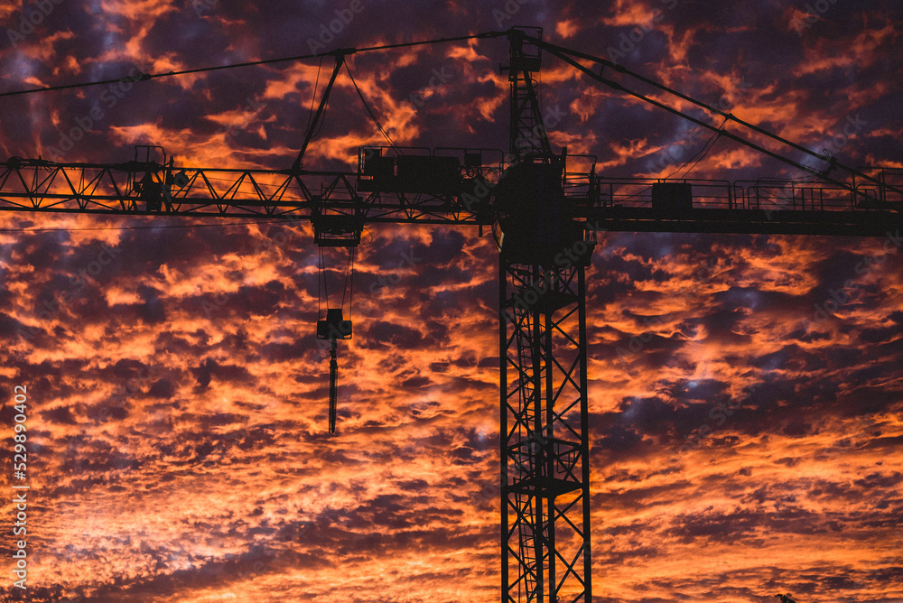 Naklejka premium Construction crane in the middle of a burning sky
