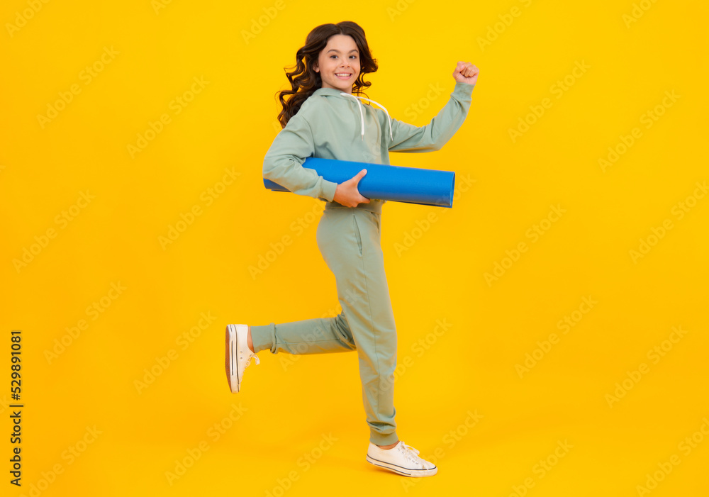 Teenage girl dressed in sports uniform, posing in the studio. Child in a posh stylish sports suit in a hoodie with a hood. Advertising sportswear and yoga wear. Healthy kids lifestyle, sport.