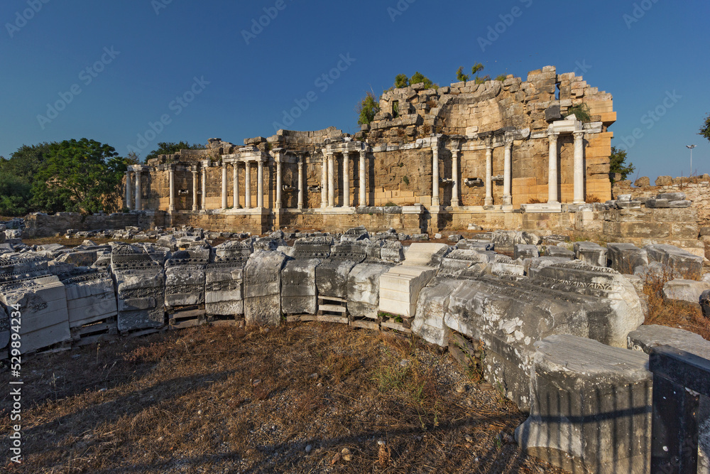 View of the ruins of the monumental ancient Roman fountain Nymphaeum with snow-white marble columns in the historic part of Antique Side, near Antalya, Turkey