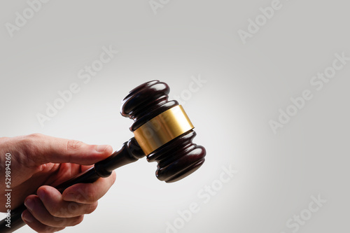 Wooden gavel of the judge in the hand of a man. Isolated on white background. Court and justice, legality, rule of law, auction. Minimalism. There is free space to insert.