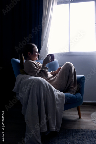 woman drinking coffee at the morning glazing the window in winter 