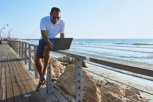 a man working remotely from the beach, portrait