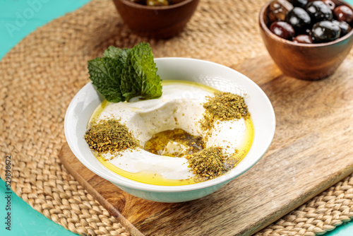 Lebneh Zaatar with olive served in a dish isolated on wooden table side view of middle eastern food