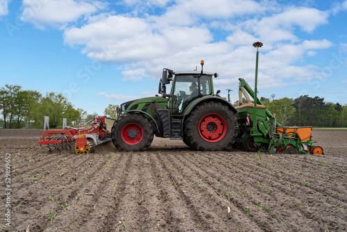 Gr  ner Traktor mit landwirtschaftlichen Ger  te beim Maislegenauf einen Feld.