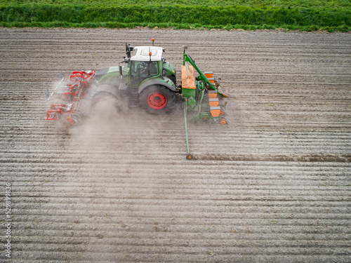 Luftaufnahme - Staubige Angelegenheit, Maissaat mit Traktor und Maschinen auf einen trockenen Acker. photo