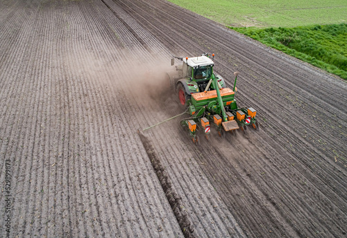 Luftaufnahme - Staubige Angelegenheit, Maissaat mit Traktor und Maschinen auf einen trockenen Acker. photo