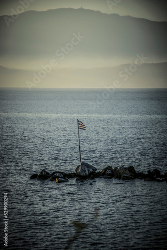 A Greek flag in the sea at Kefalonia in the evening © Jovana