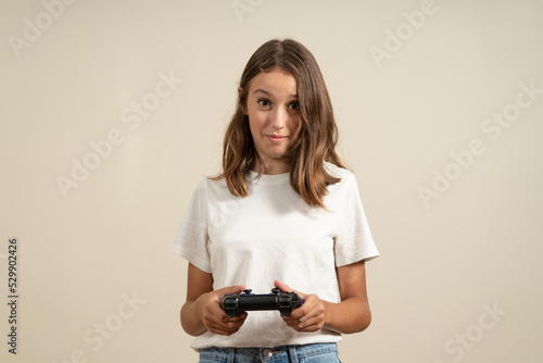 Portrait of cute active and energetic teenage girl having vacation using video game console feeling satisfied wearing t-shirt isolated on colorful background.