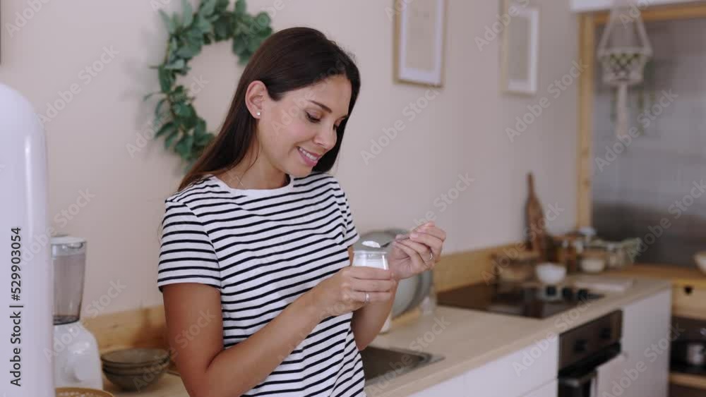 Pretty young adult woman eating natural yogurt while standing in the kitchen at home - Healthy lifestyle concept Pretty young adult woman eating natural yogurt while standing in the kitchen at home - Healthy lifestyle concept