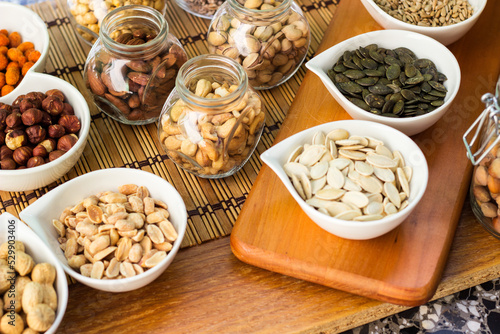 Rustic wood table filled with a large assortment of nuts like pistachios, hazelnut, pine nut, almonds, pumpkin seeds, sunflower seeds, peanuts, cashew and walnuts