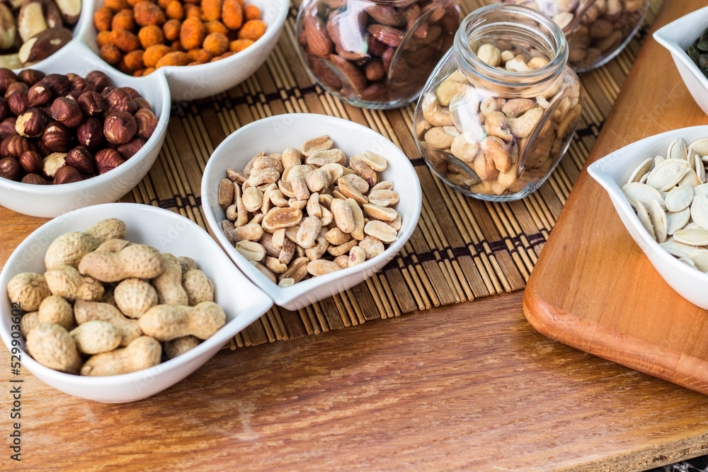 Rustic wood table filled with a large assortment of nuts like pistachios, hazelnut, pine nut, almonds, pumpkin seeds, sunflower seeds, peanuts, cashew and walnuts Rustic wood table filled with a large assortment of nuts like pistachios, hazelnut, pine nut, almonds, pumpkin seeds, sunflower seeds, peanuts, cashew and walnuts