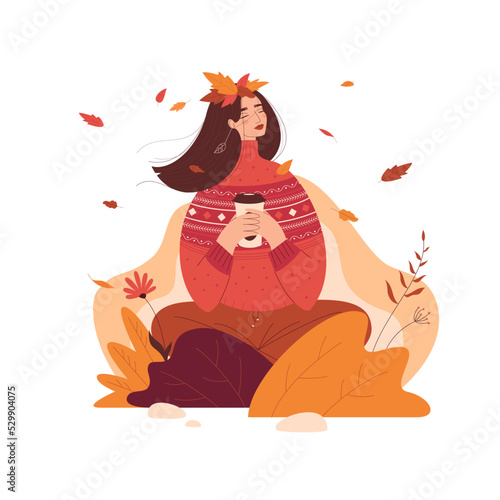 Happy girl in a warm sweater drinking coffee or tea and enjoying the autumn nature.