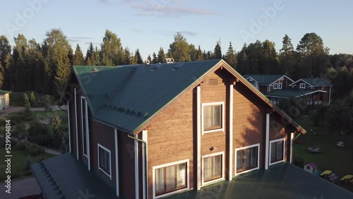 wooden country house in a cottage village on a summer recreation center among green trees. guest house in the rays of the sun. Hunting lodge shooting from a height from a drone.