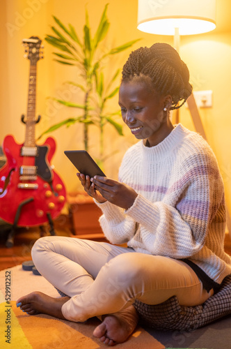 фотографія Young woman reading a kindle or ebook  while sitting on the floor at home