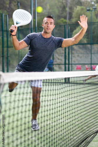 Caucasian man in sportswear playing padel tennis match during training on court.